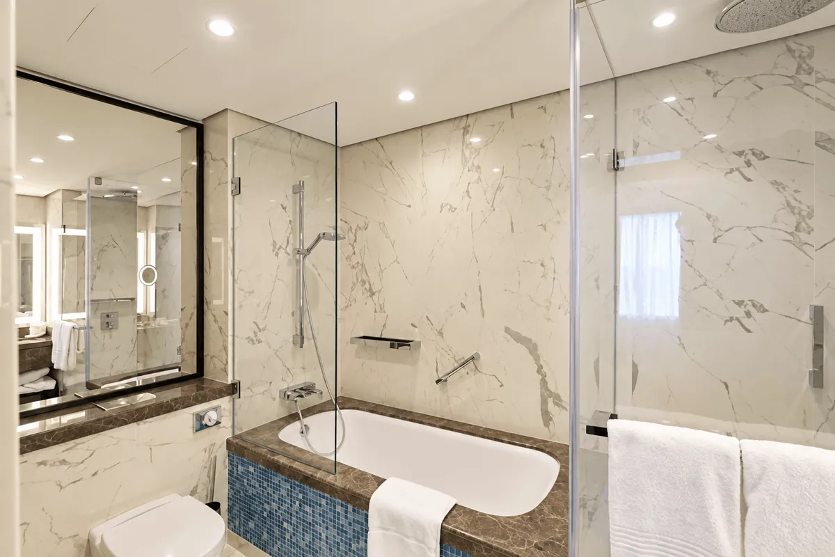 Baie cu marmură, cadă și cabină de duș din sticlă, la Howard Johnson Grand Plaza