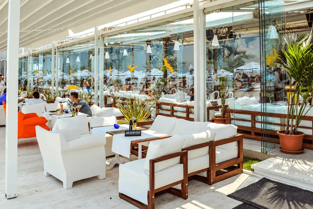 Terasa Fratelli Beach & Club cu canapele albe și plante